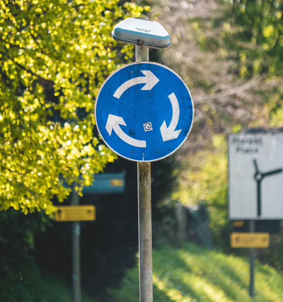Blue sign with 3 white arrows forming a circle (sign is to show a roundabout on UK roads)
