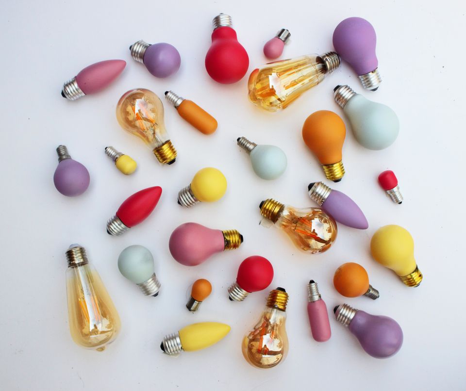 Colourful pink, red, yellow, and purple lightbulbs laid on a white surface